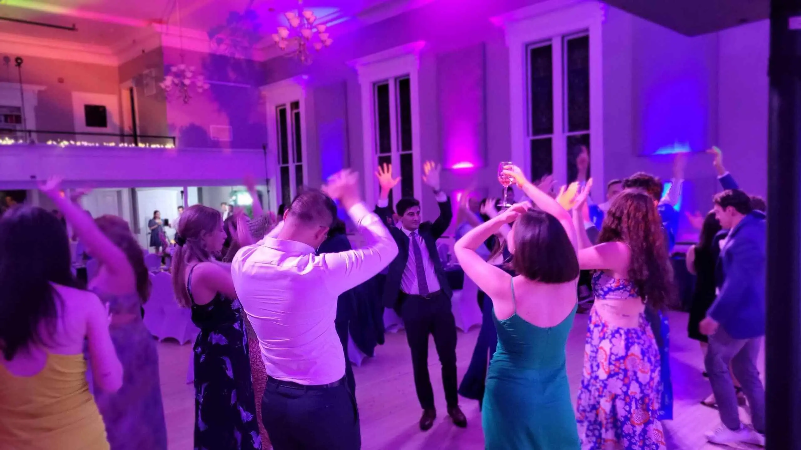Function room washed in purple uplighting with guests on the dance floor